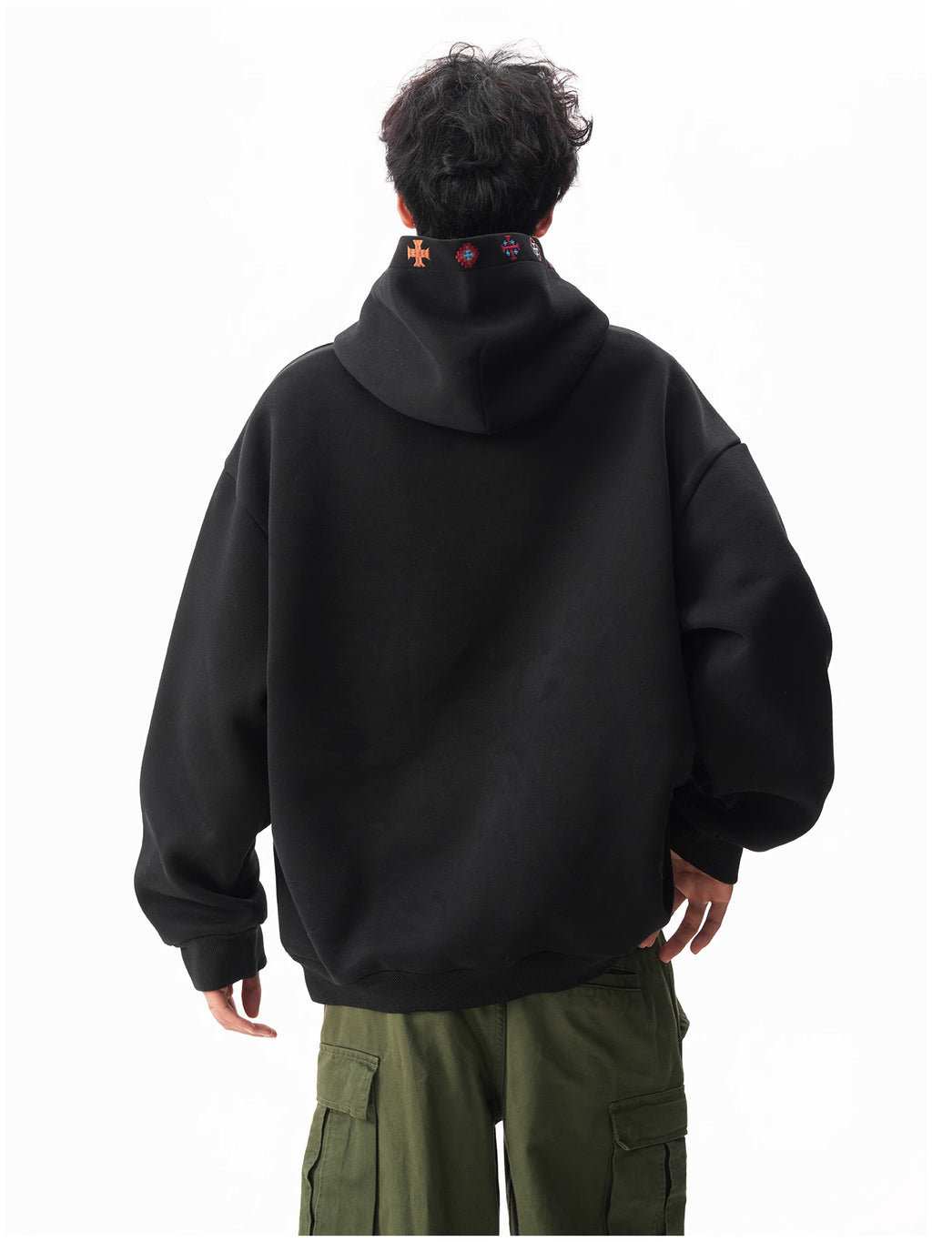 Person wearing a black hoodie with colorful designs on the hood, standing against a white background.