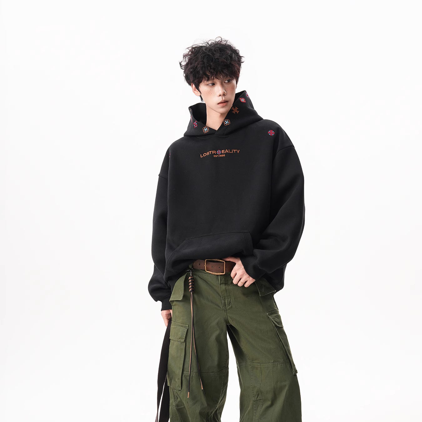 Person wearing a black hoodie and green pants with a white background